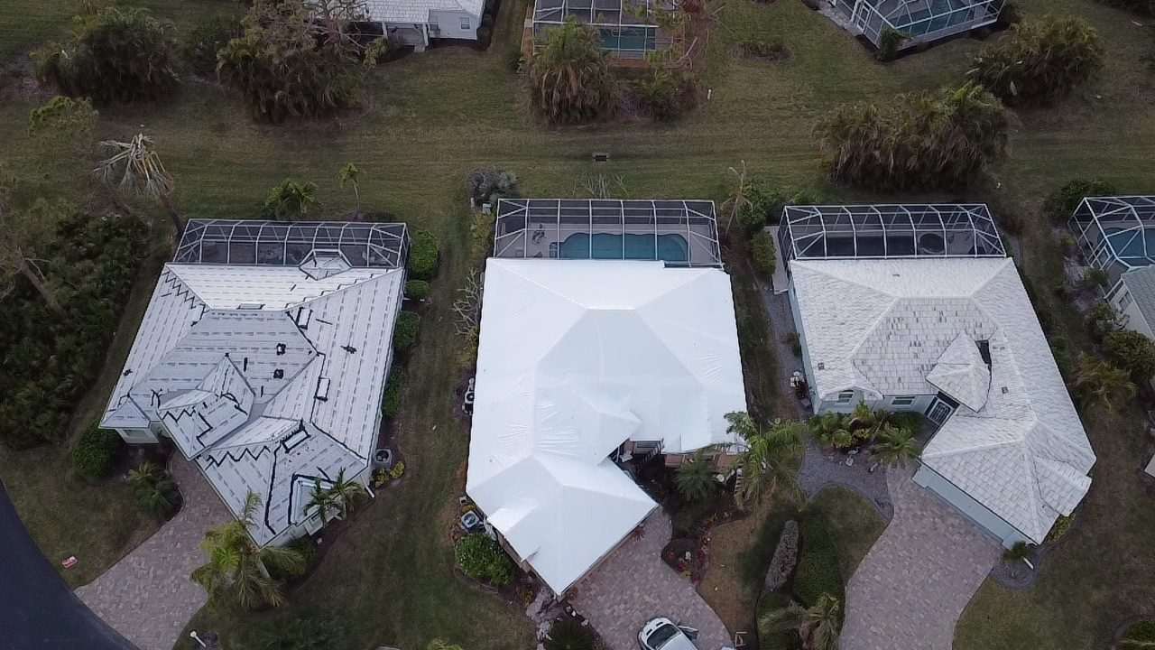 Two wrapped roofs side by side on a canal street, screened pool enclosures alongside each