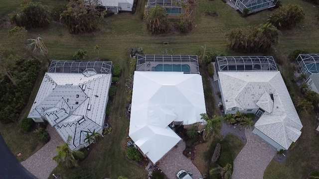 Two wrapped roofs side by side on a canal street, screened pool enclosures alongside each