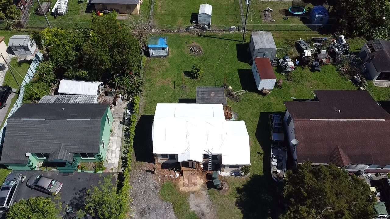 Wrapped roof seen from above on a lot with sheds and outbuildings around it