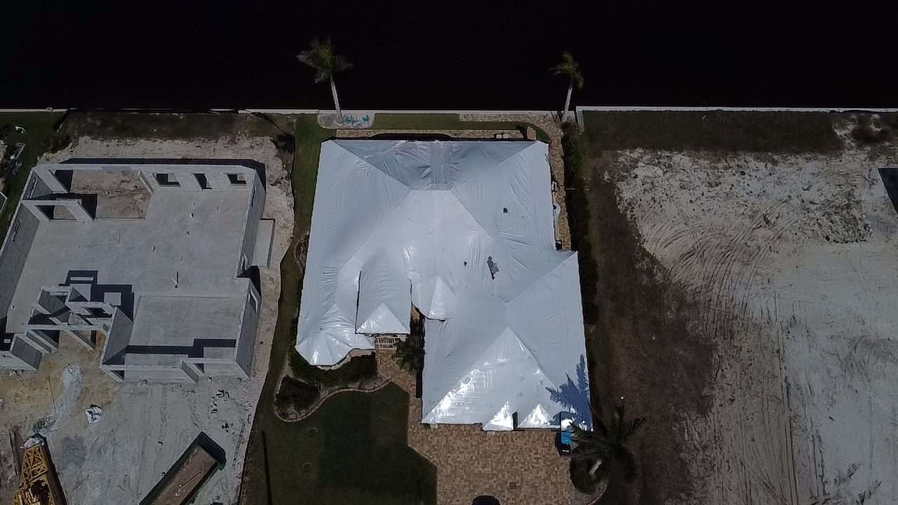 Roof wrapped in white beside a cleared building lot, seen from directly overhead