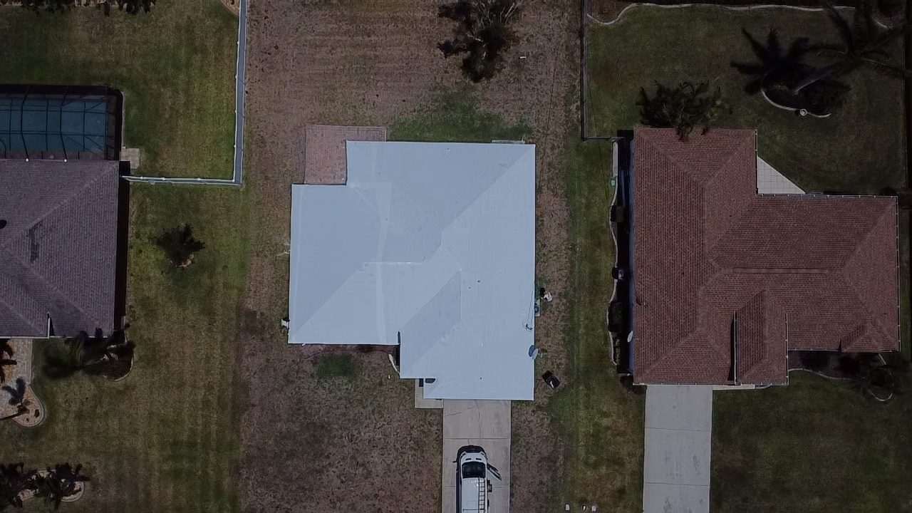 Shrink-wrapped roof between two tile-roofed neighbors, a ladder standing at the garage