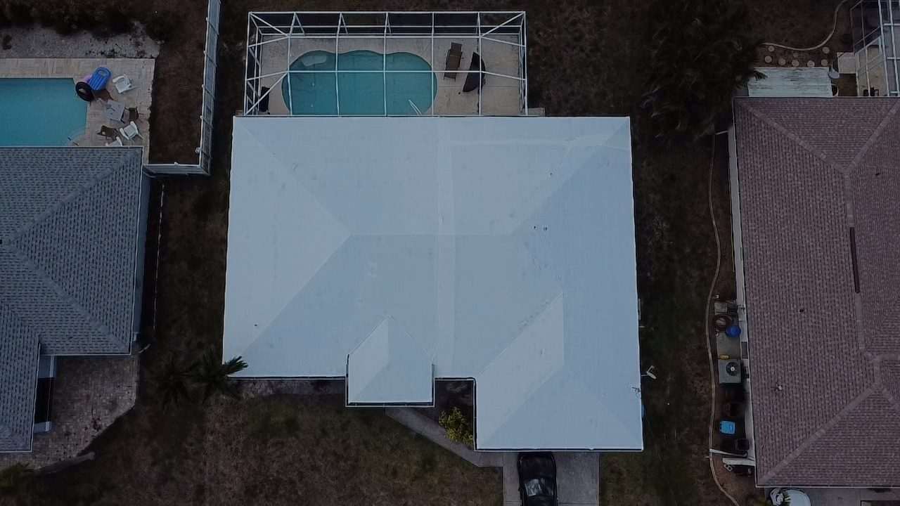 Close aerial of a large wrapped roof with the screened pool deck alongside