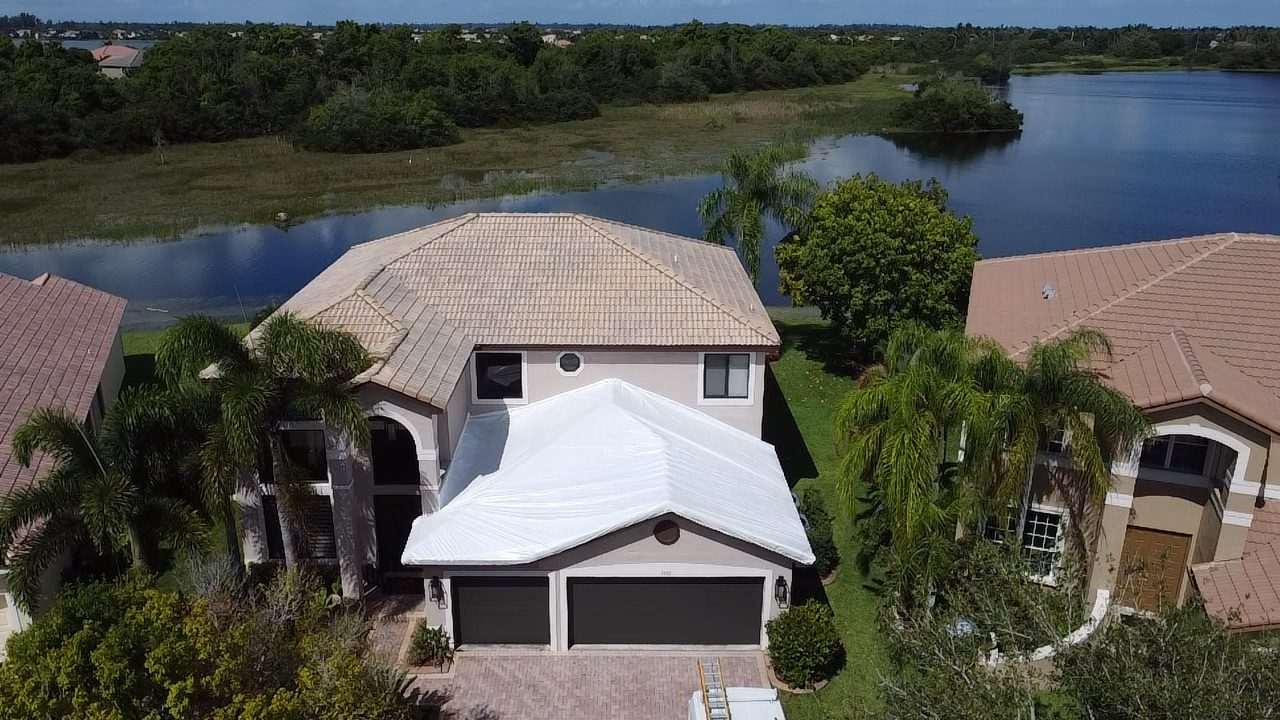 The same lakefront home from the other side, white wrap sealed over the front slope