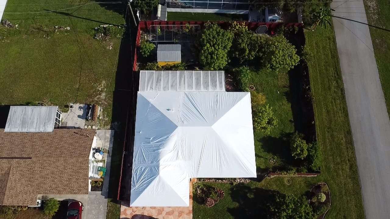 Overhead view of a wrapped roof on a fenced lot, red boundary fence around the garden