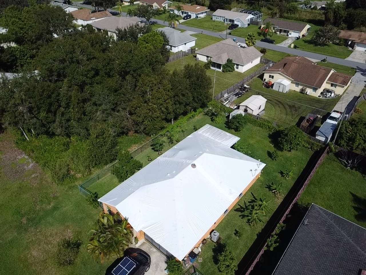 Long wrapped roof running the depth of the lot, trees on both sides