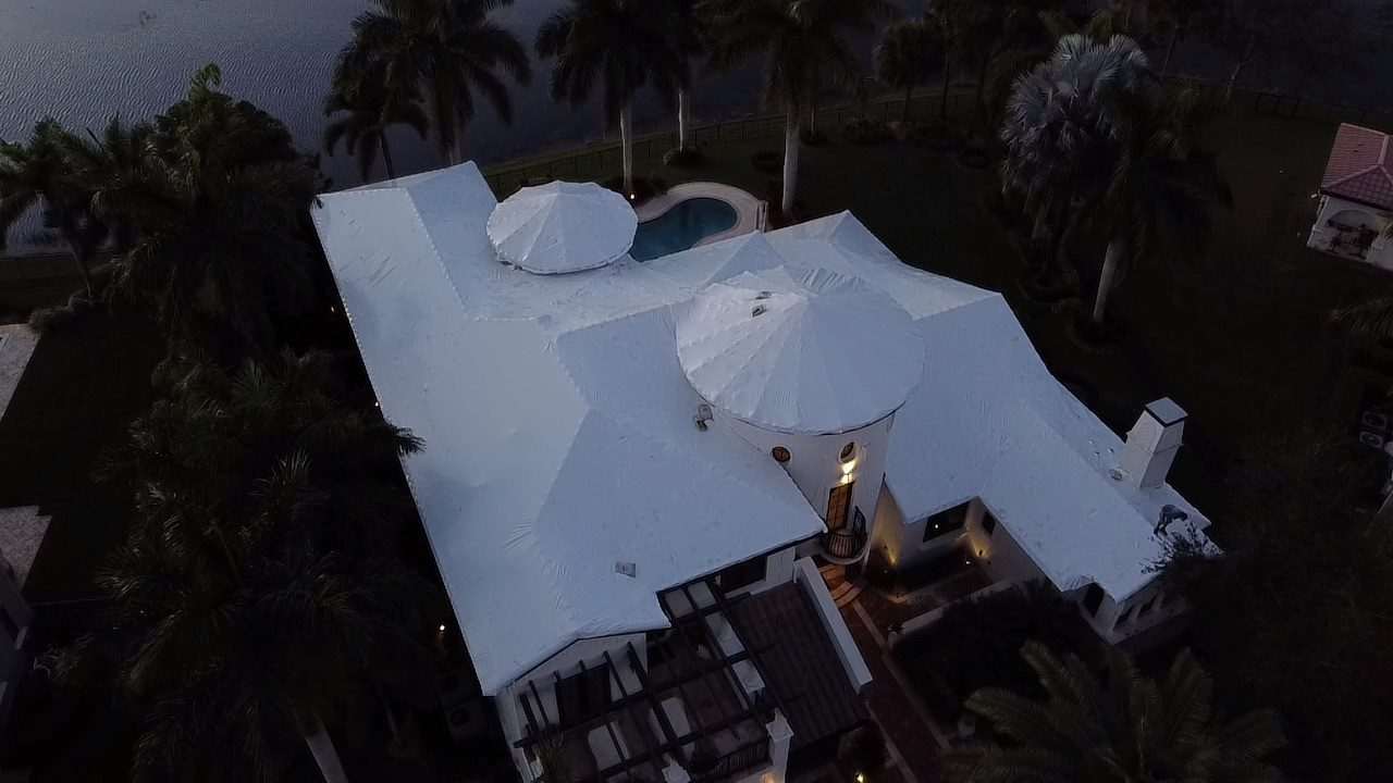 Large lakefront home with every roof section wrapped in white, including the two domed turrets