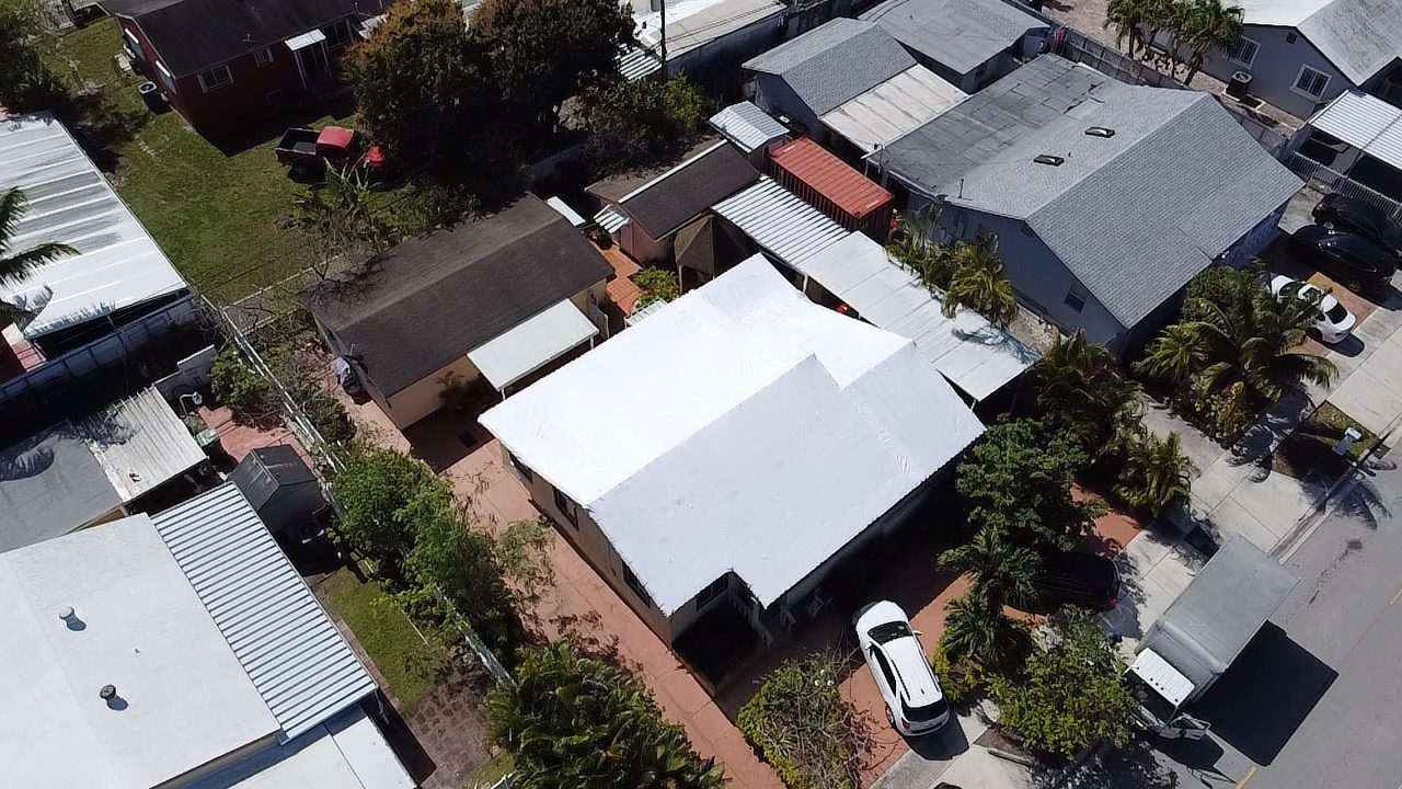 The same block from a different angle, the wrapped roof bright against the metal roofs around it