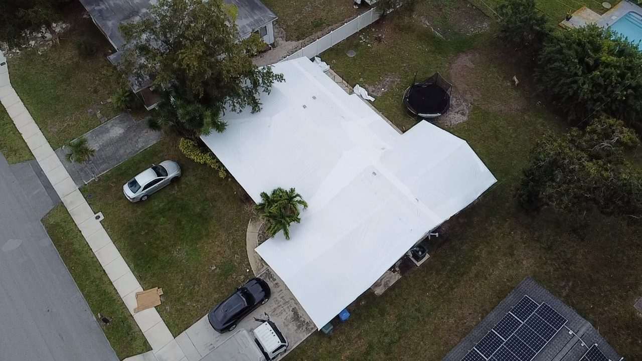 White-wrapped roof on a street-front lot, trampoline and pool in the yards behind